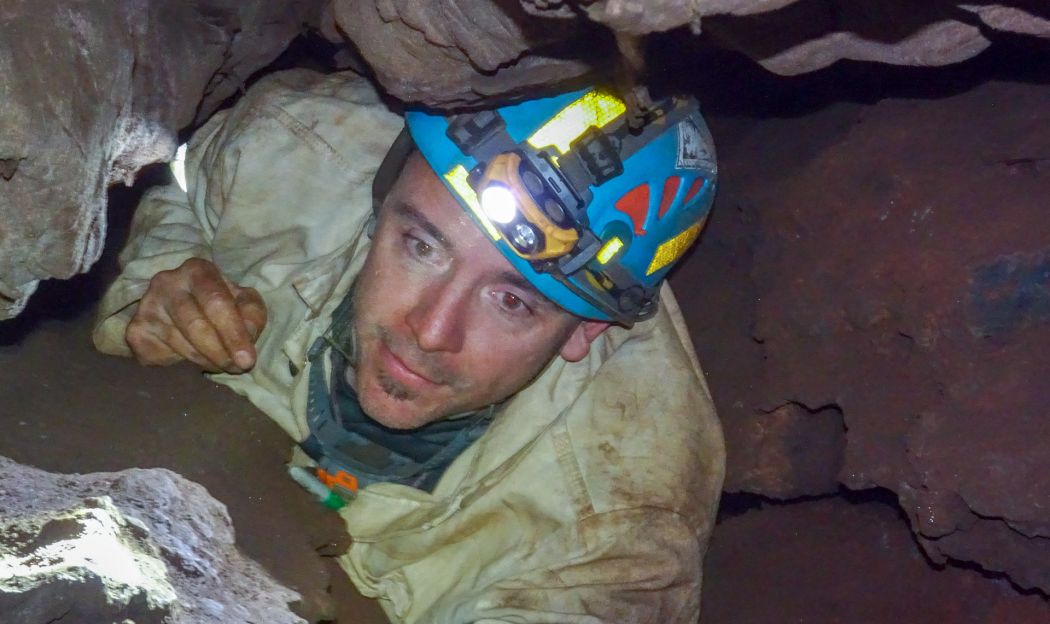 Man in cave wearing helmet. 