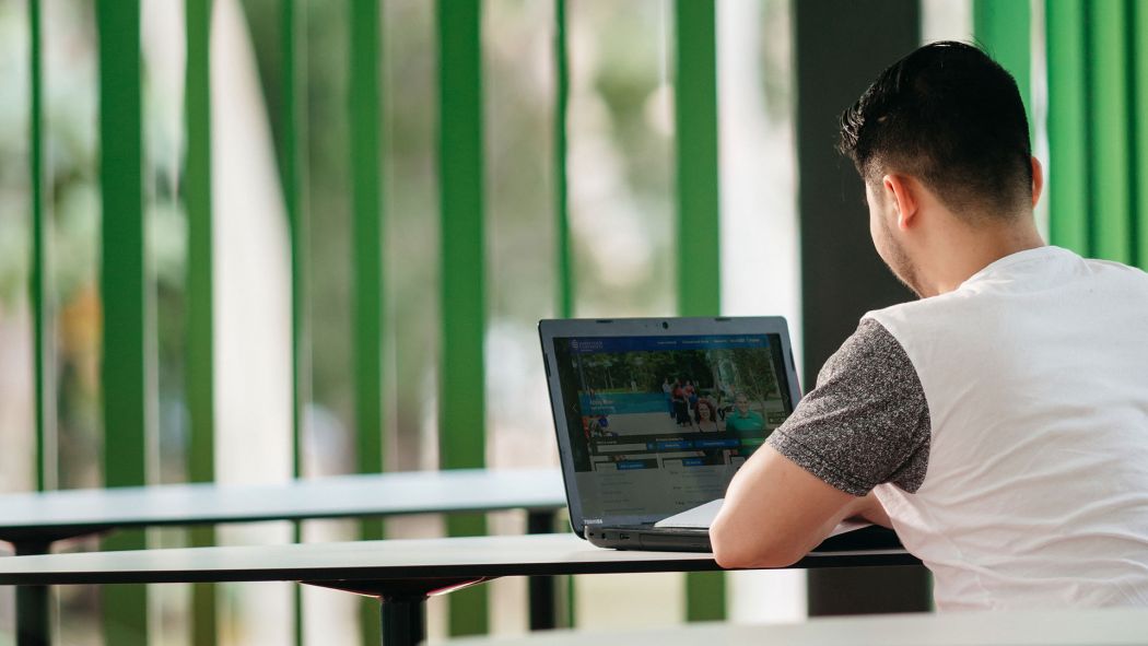 Male student facing computer while studying in the Verandah Walk at  Townsville, Bebegu Yumba campus, Douglas. 