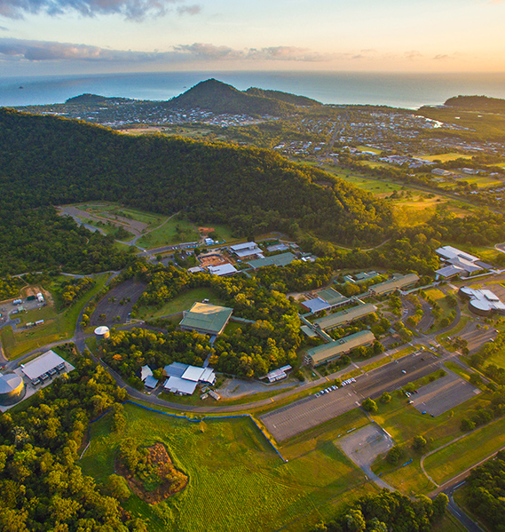An aerial view of  Cairns campus, surrounded by mountains and with the sea in the background. 