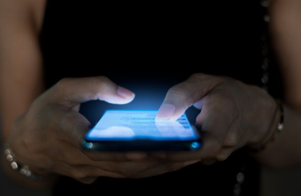Close up of one person's hands holding a phone that is lighting up the dark around them. 
