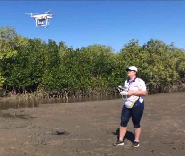  PhD student Sophie Walker standing while operating a drone flying in front of her. 