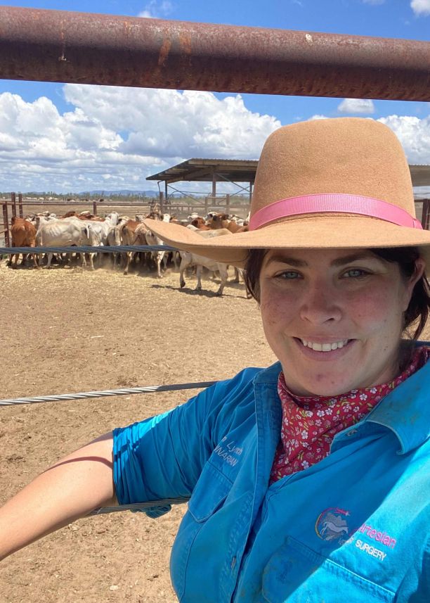  Alumni and veterinarian Regan Lynch smiling and standing in front of a cattle yard. 